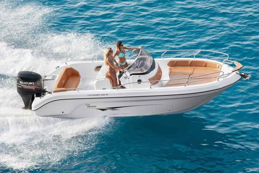 White Ranieri Voager 23s motorboat speeding on blue water with two people aboard and a tan deck area