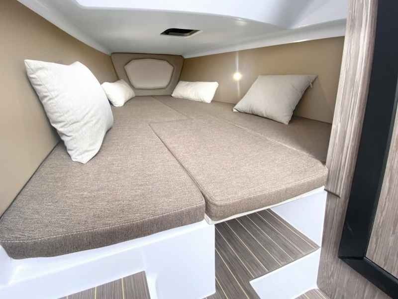 Cozy beige cabin berth with cushioned mattress and white pillows in a compact interior