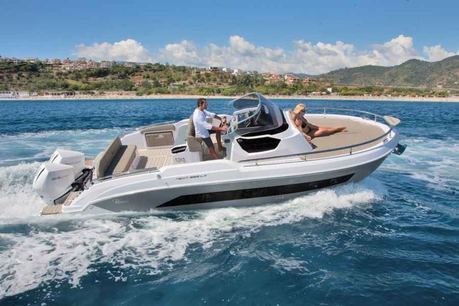 White speedboat with people cruising on blue water near a shoreline under a sunny sky