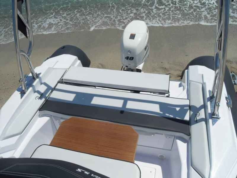 Boat stern view with white deck, wood step, and outboard motor near the waterline