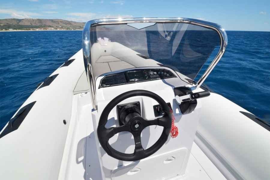 ranieri cayman 26 sport Motorboat helm with windshield on calm blue water near a rocky coastline
