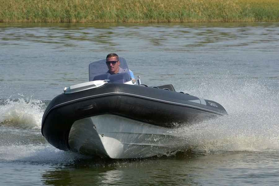 grand golden line 420 Black speedboat racing across water with a person driving, spraying white wake