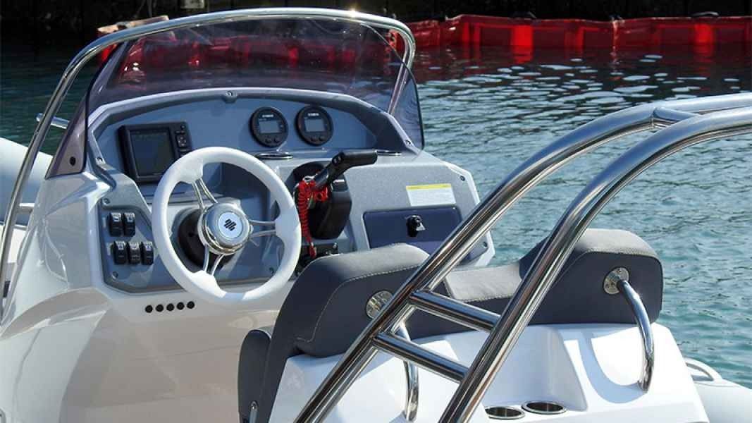 Boat cockpit with steering wheel and gauges on a sunny lake, seen from the stern.