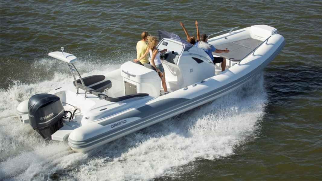 White grand golden line 850 motorboat speeding across choppy water with two people onboard, leaving a foamy wake