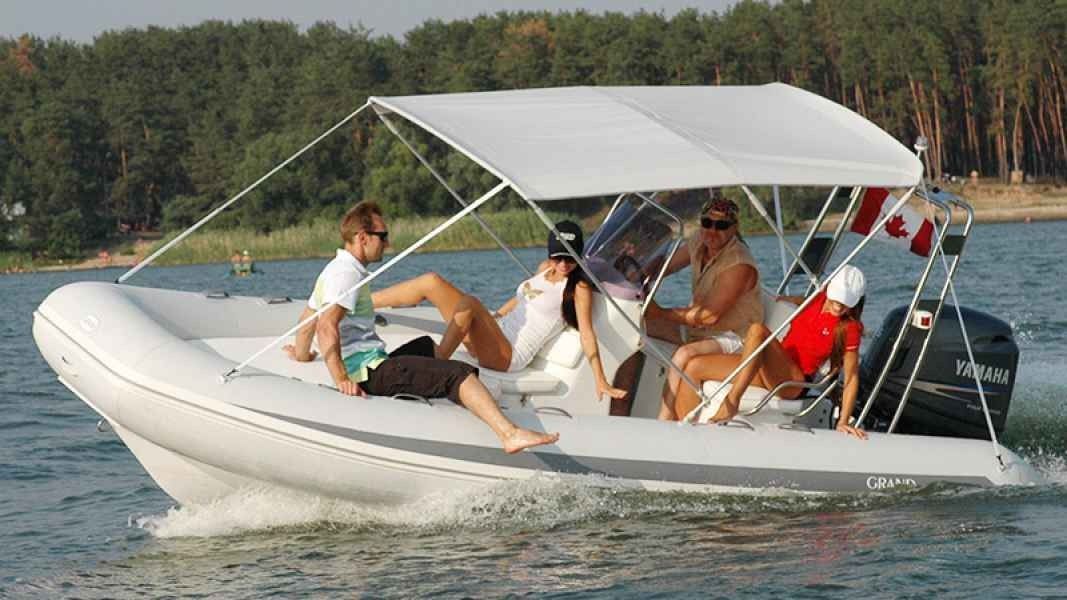 Inflatable grand silver line 520 boat speeding on water with several people under a white canopy