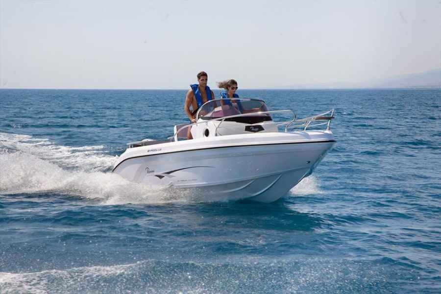 White motorboat speeding on blue water with two people aboard