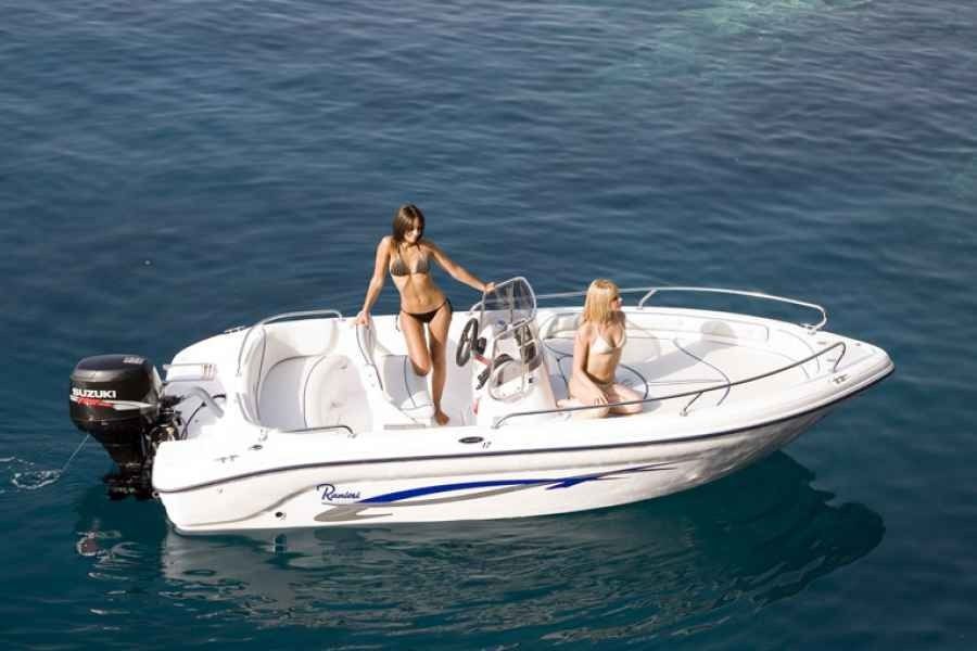 Two people on a white ranieri voyager 17 motorboat on calm blue water, one standing and one seated.