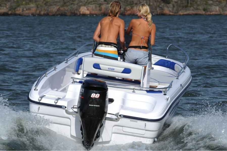Two people sit on the stern of a ranieri voyager 19 speedboat, riding across choppy blue water.