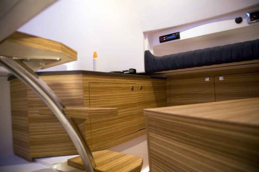 Modern wood-paneled cabin interior with built-in bed, drawers, and a curved metal railing in ranieri voyager 30 Sport boat