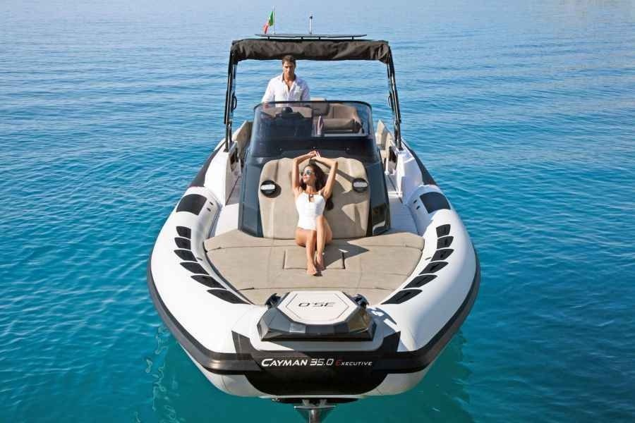 People on a white Ranieri Cayman 35 Executive motorboat on calm blue water, with one person on the bow and one at the helm.