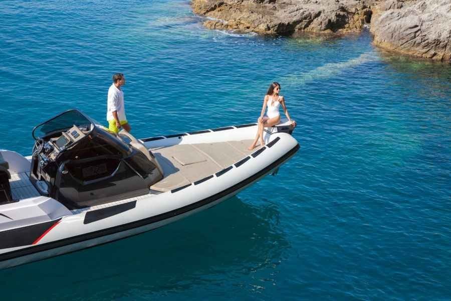 Two people on a Ranieri Cayman 35 Executive motorboat in clear blue water near rocky shore