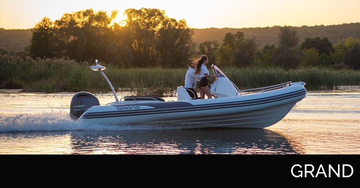 Small motorboat speeding across a calm lake at sunset, with two people onboard and a