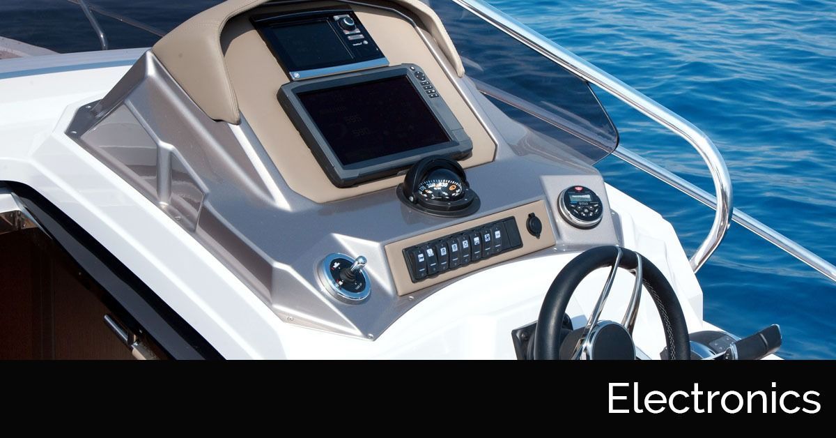Boat electronics console with display screen, buttons, and steering wheel on a yacht deck
