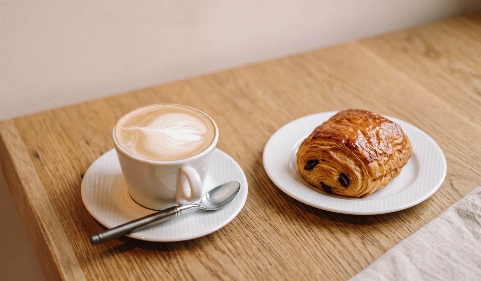 a cup of artisan cappuccino served with a slice of pain au chocolait