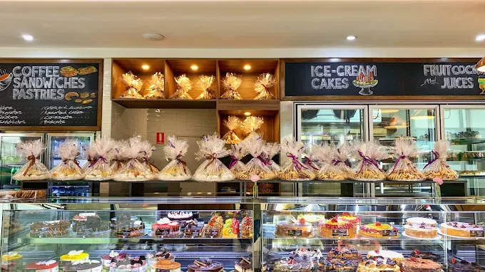 profiterole patisserie penrith employee holding two cakes