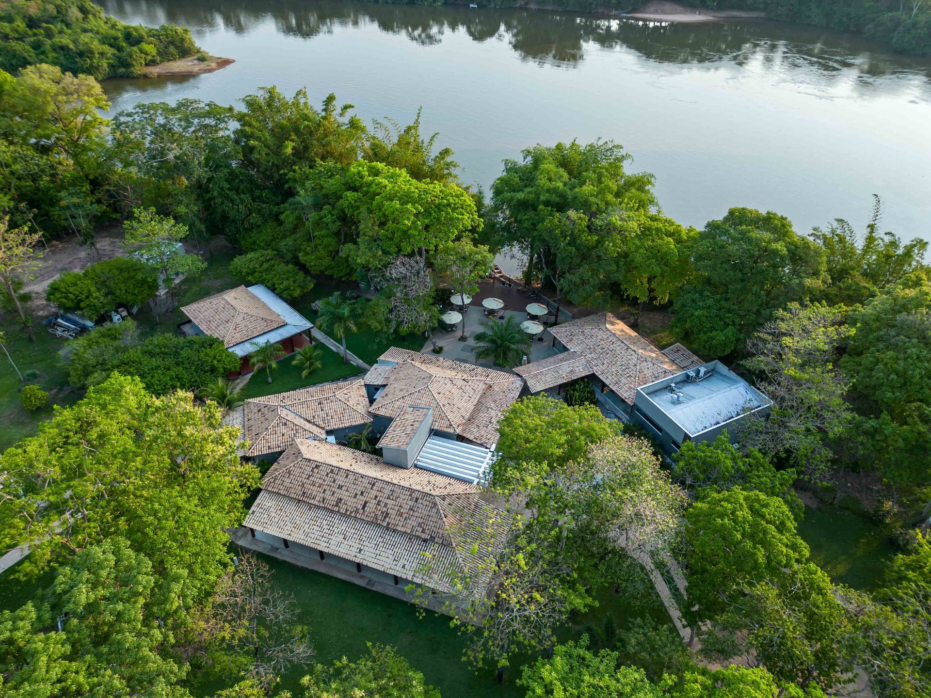 Uma vista aérea de uma casa cercada por árvores próxima a um corpo d'água.