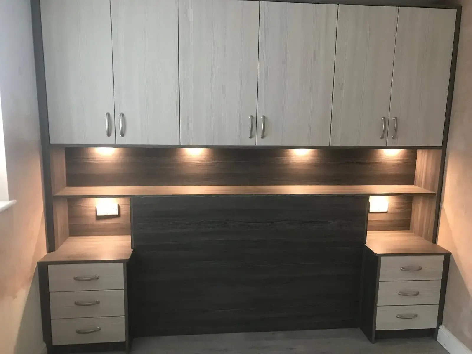 Modern L-shaped kitchen with light gray cabinets, white countertops, black oven and hood, and a farmhouse sink.