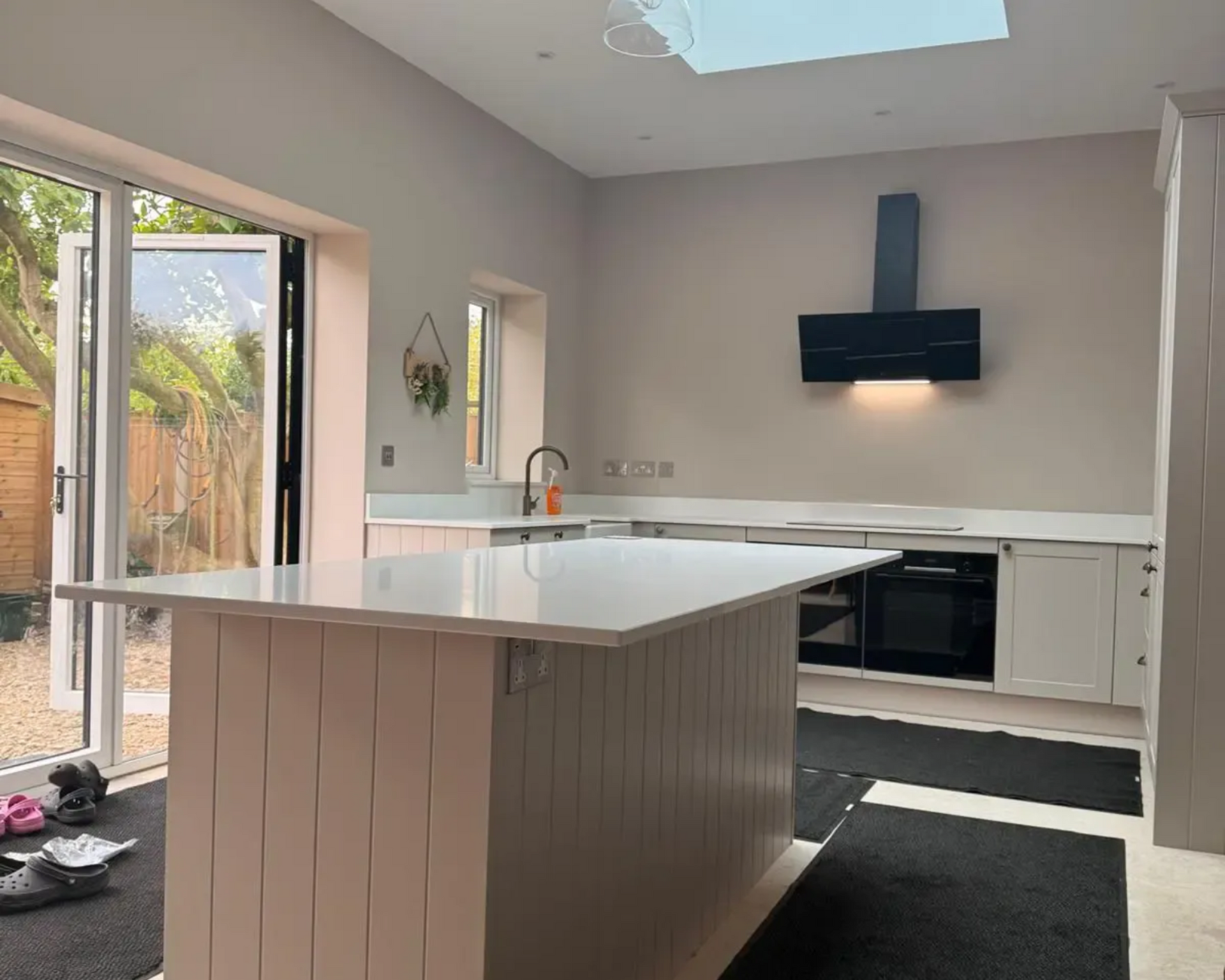 Modern kitchen with white island, black appliances, and sliding glass doors to a patio