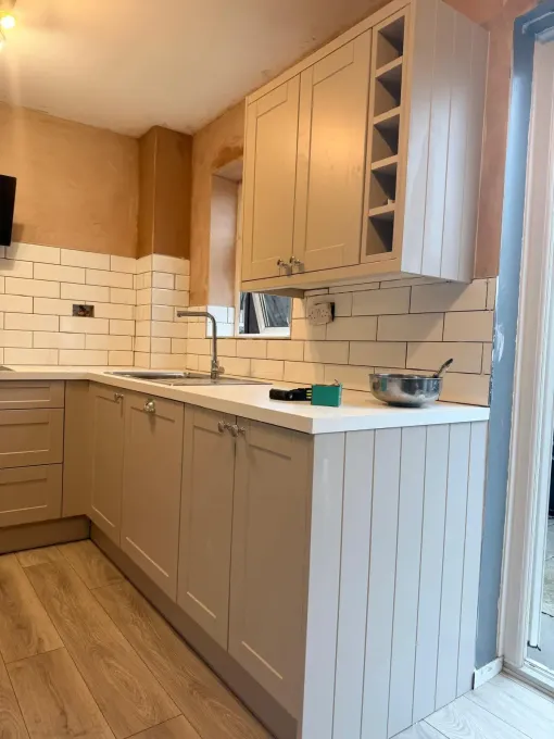 Small beige kitchen with white subway tile backsplash, light wood cabinets, and wood flooring.