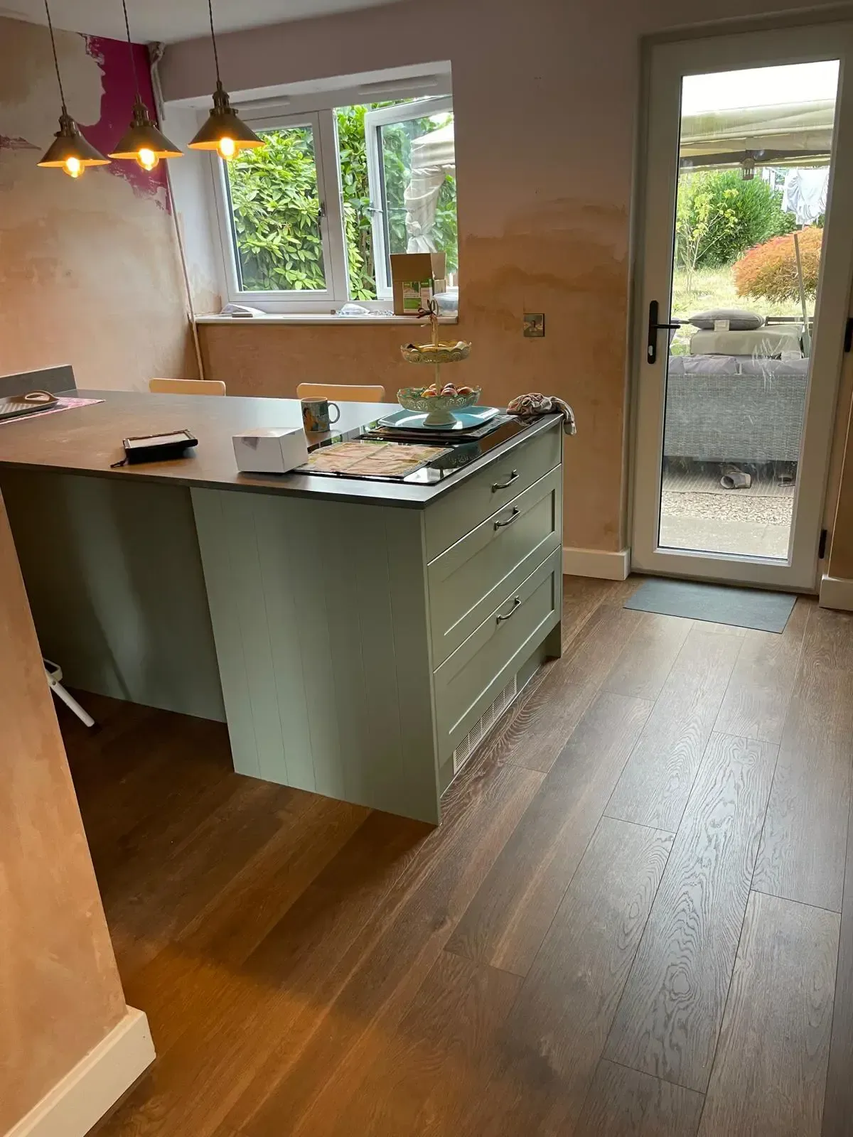 Modern L-shaped kitchen with light gray cabinets, white countertops, black oven and hood, and a farmhouse sink.