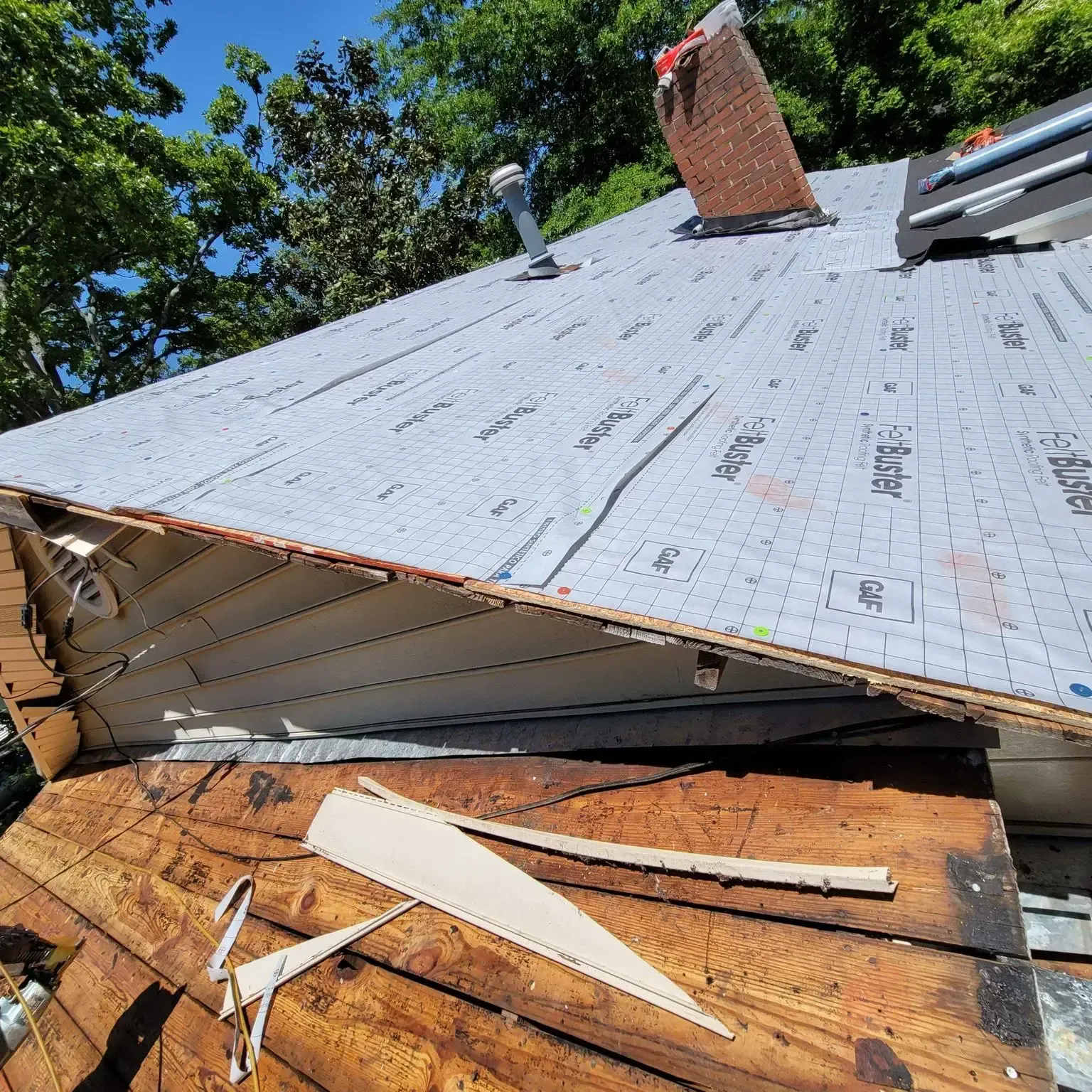 Roof under construction with exposed wood, sheathing, and roofing material.