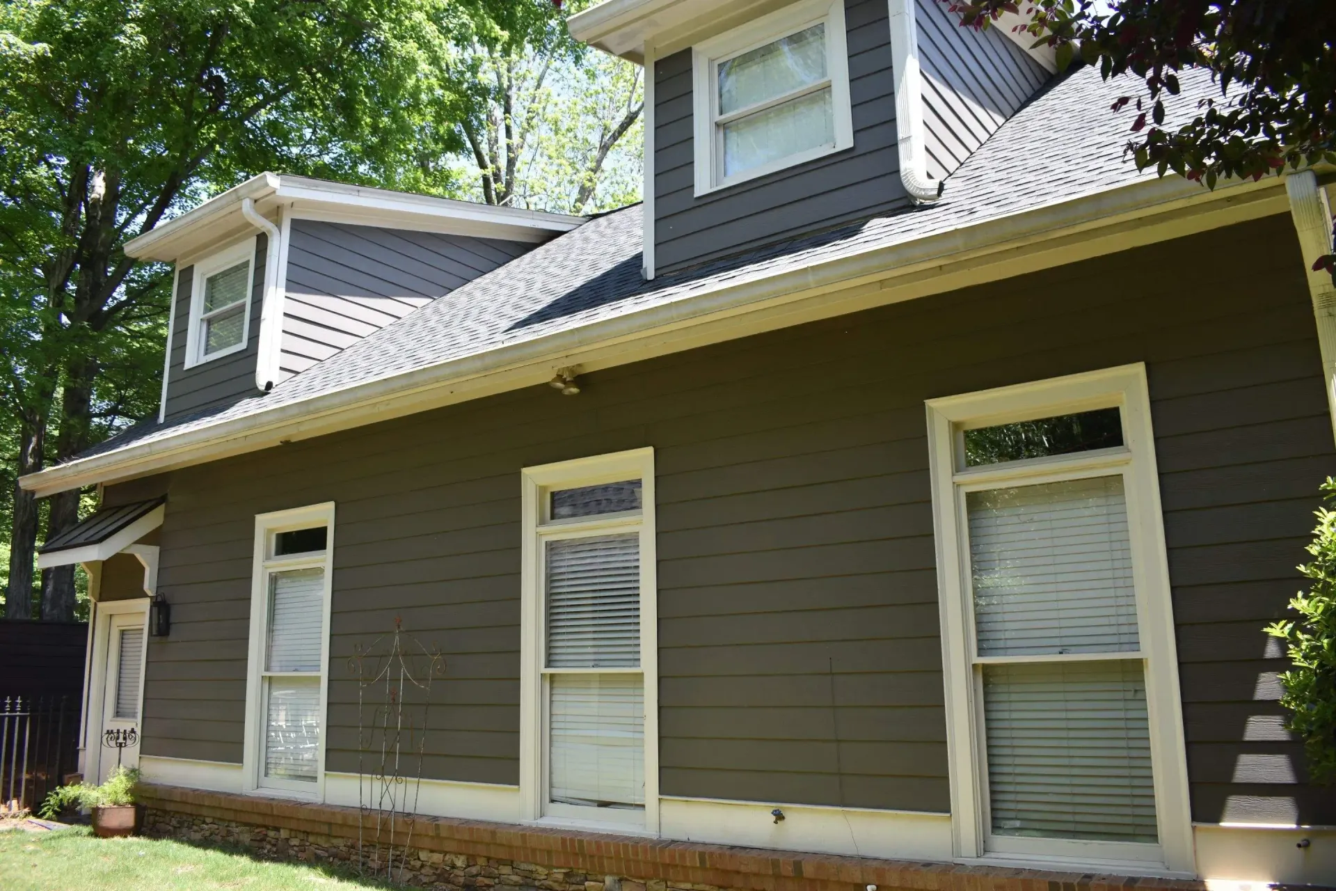 Two-story house with dark gray siding, white trim, and dormer windows.