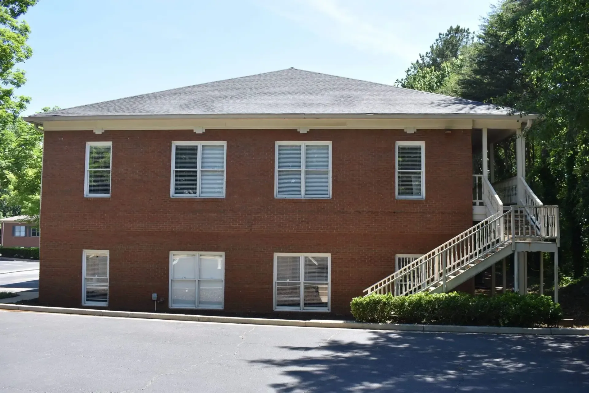 Two-story brick building with windows and outdoor staircase.