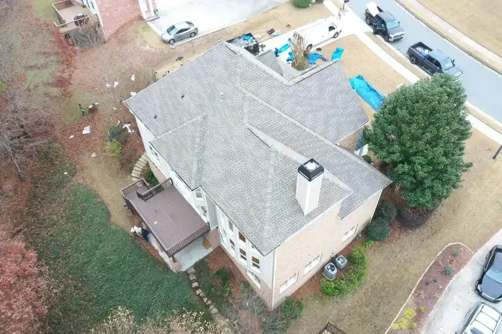 Aerial view of a two-story house with a gray roof and a pool in the backyard.