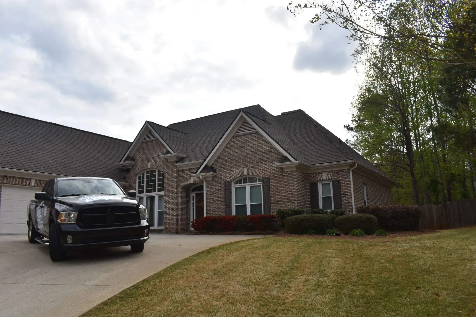 Black pickup truck parked in front of a brick house with a curved driveway and lawn.