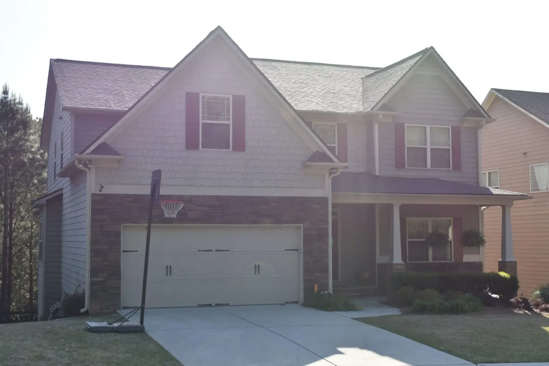Two-story house with gray siding, a stone facade, and a two-car garage.