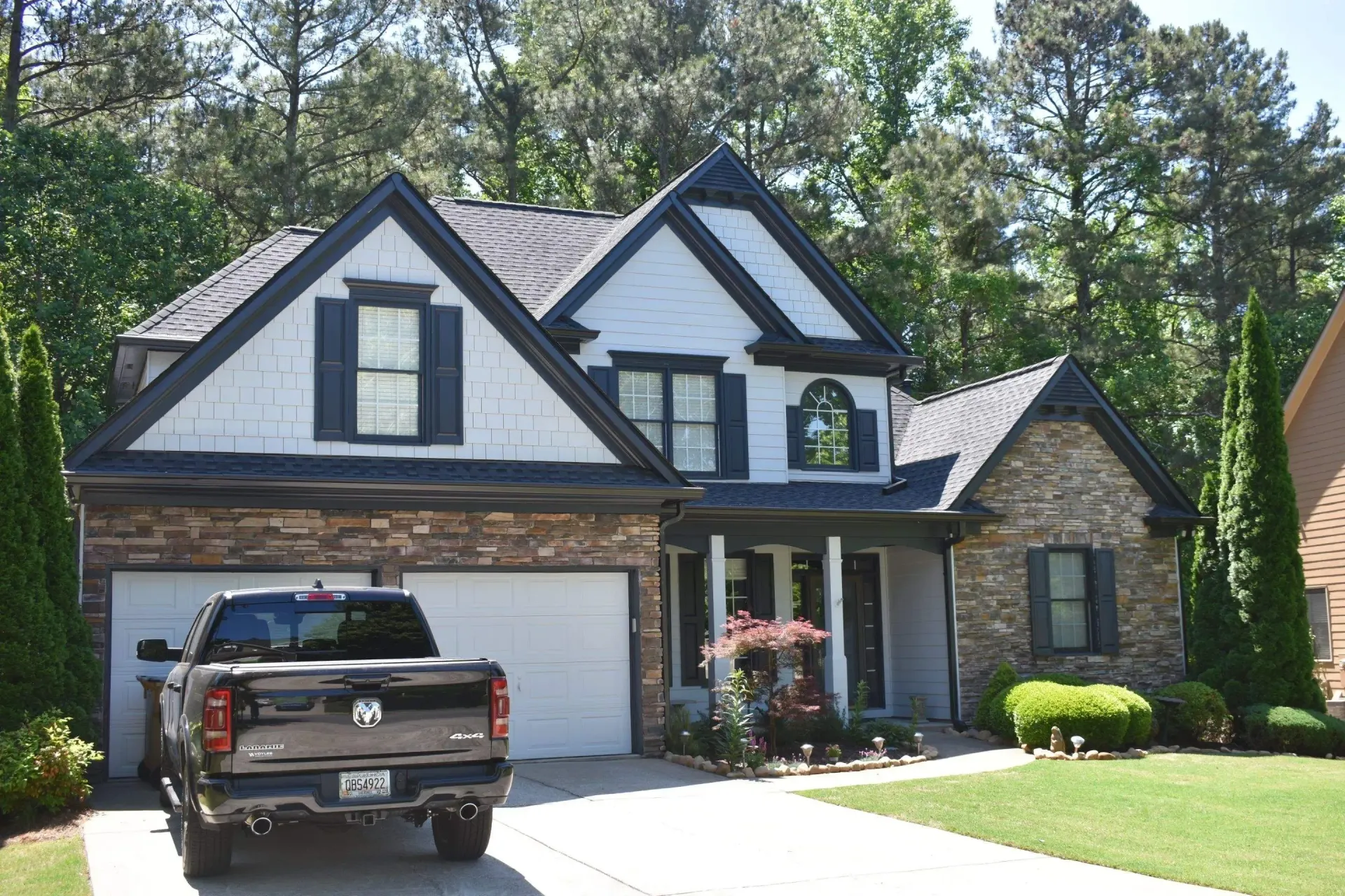 Brown house with a pickup truck in the driveway. The house has a stone facade, white trim, and a black roof.