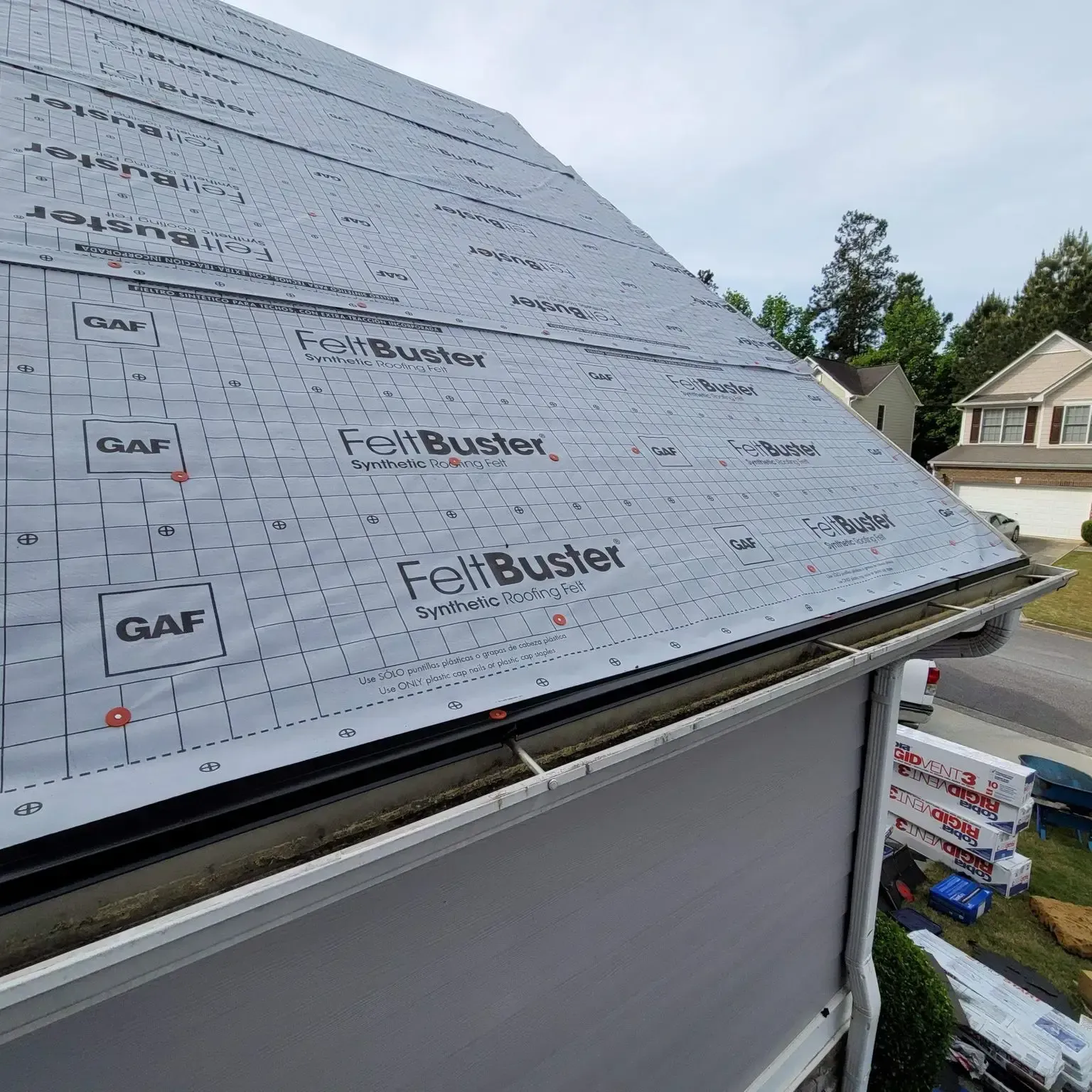 Roof with grey synthetic underlayment, near gutters, and building materials.
