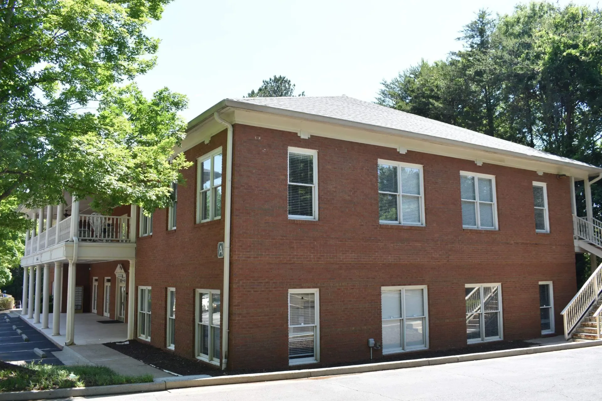 Two-story brick building with windows; trees in the background, daytime.