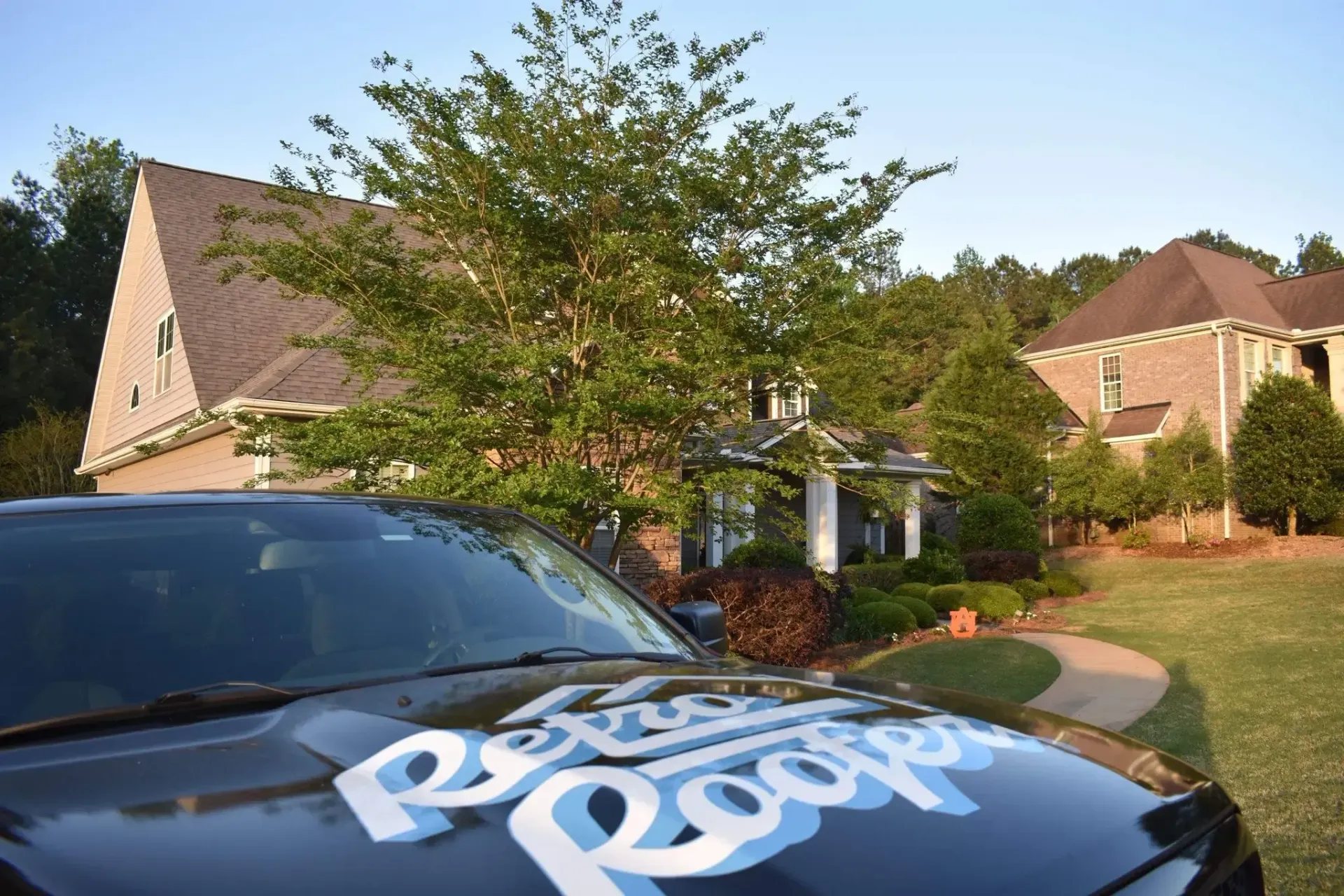 Blue and white logo on car hood in front of a house.
