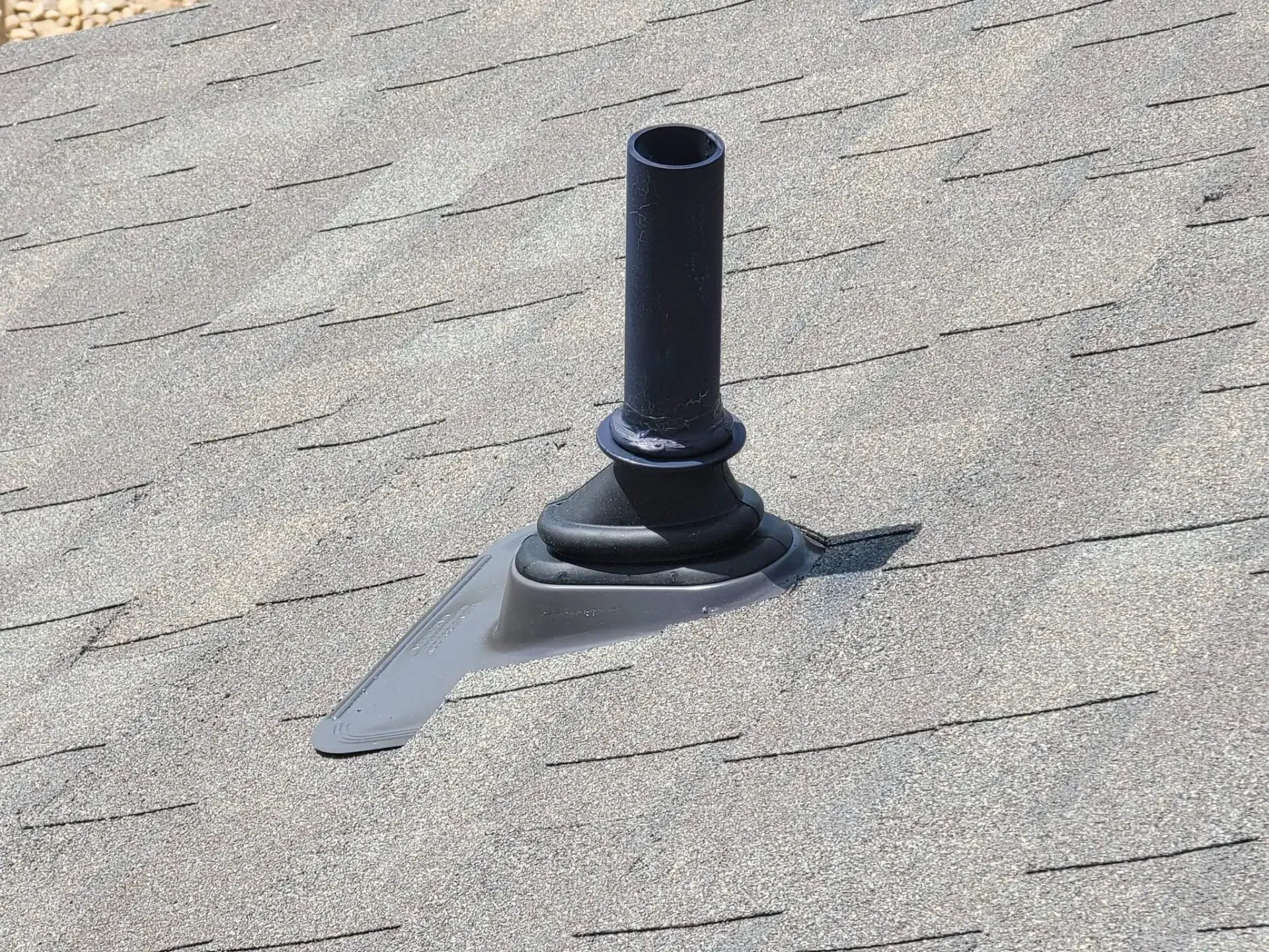 Black pipe vent on a gray shingle roof.