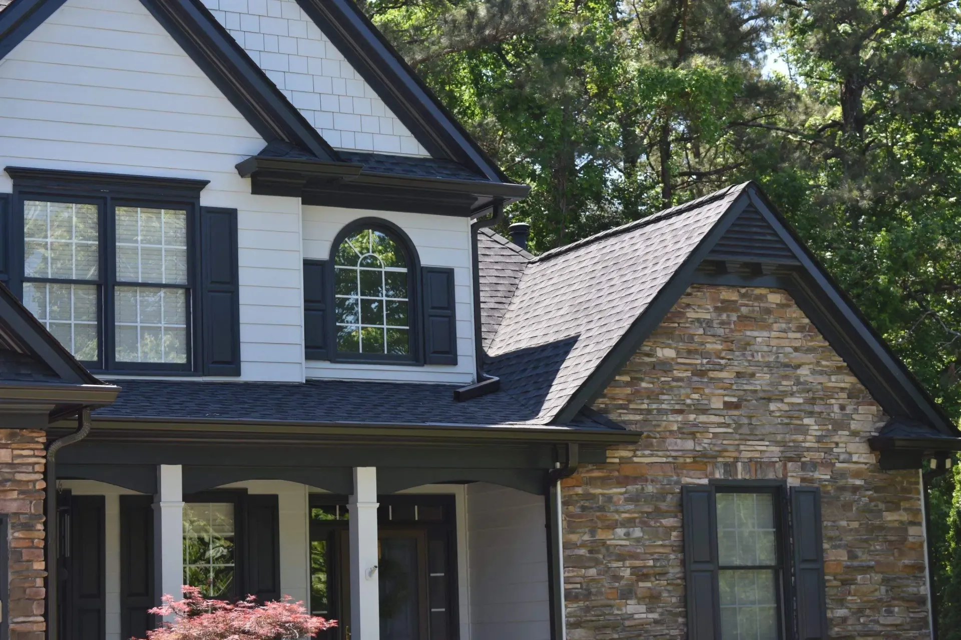 Two-story house with white siding, dark trim, and stone accents.