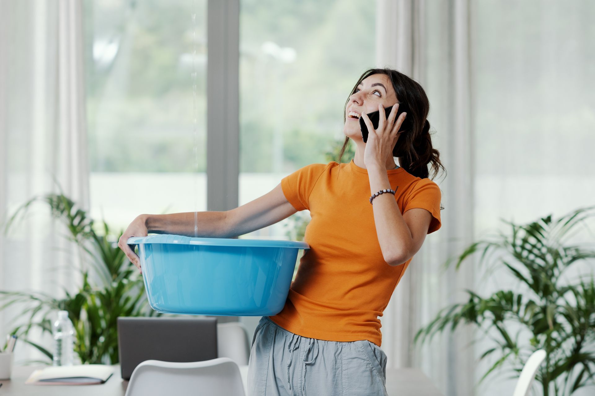 woman with bucket catching water from a roof leak