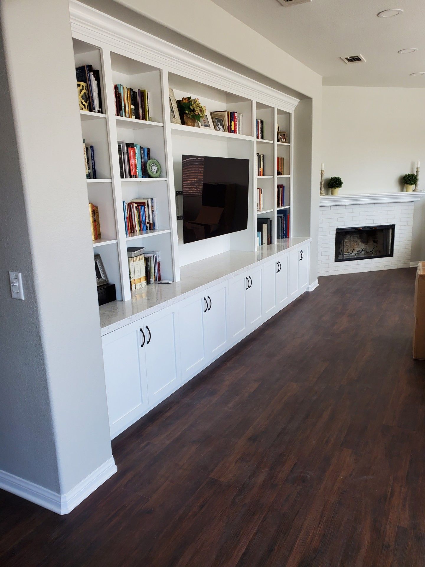 Bright built-in white shelving with decor and plants in a sunlit living room.