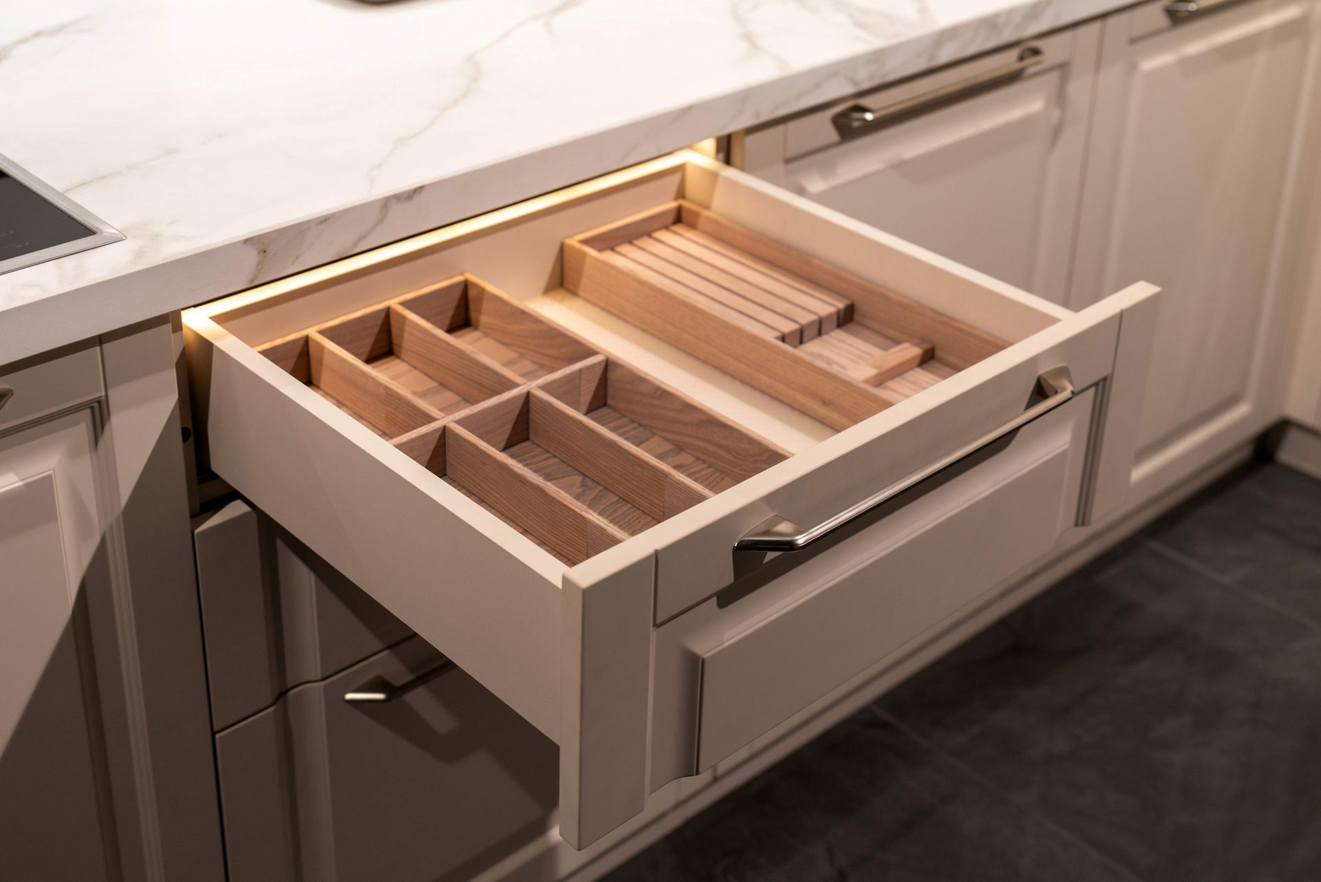 Open kitchen drawer with wooden cutlery organizer and compartments
