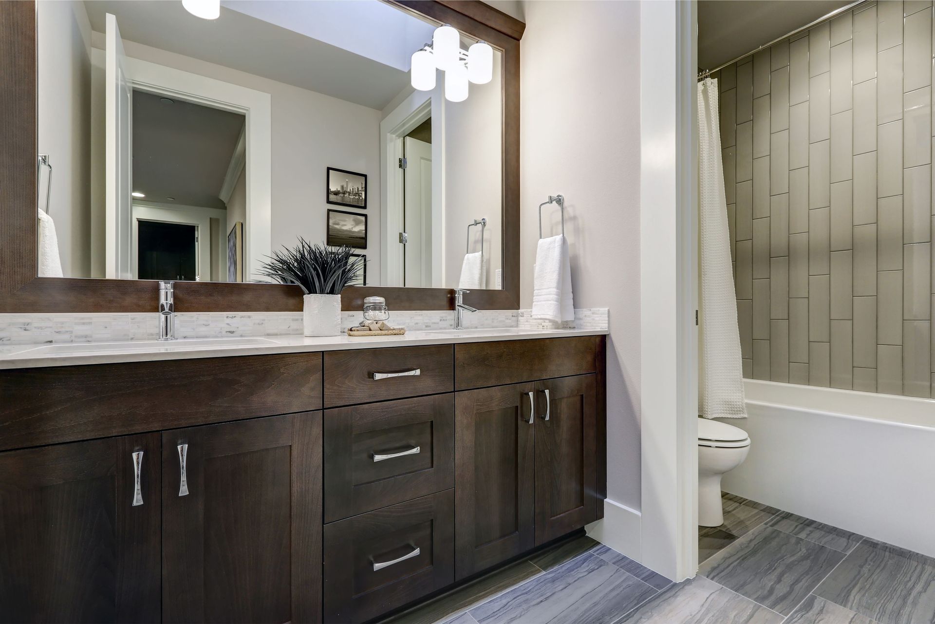 Modern bathroom vanity with dark wood cabinets, large mirror, and shower curtain beside the toilet