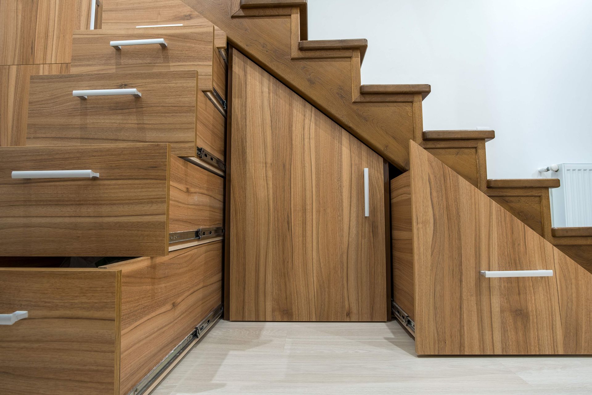 Wooden staircase with built-in storage drawers and a concealed cabinet door underneath.
