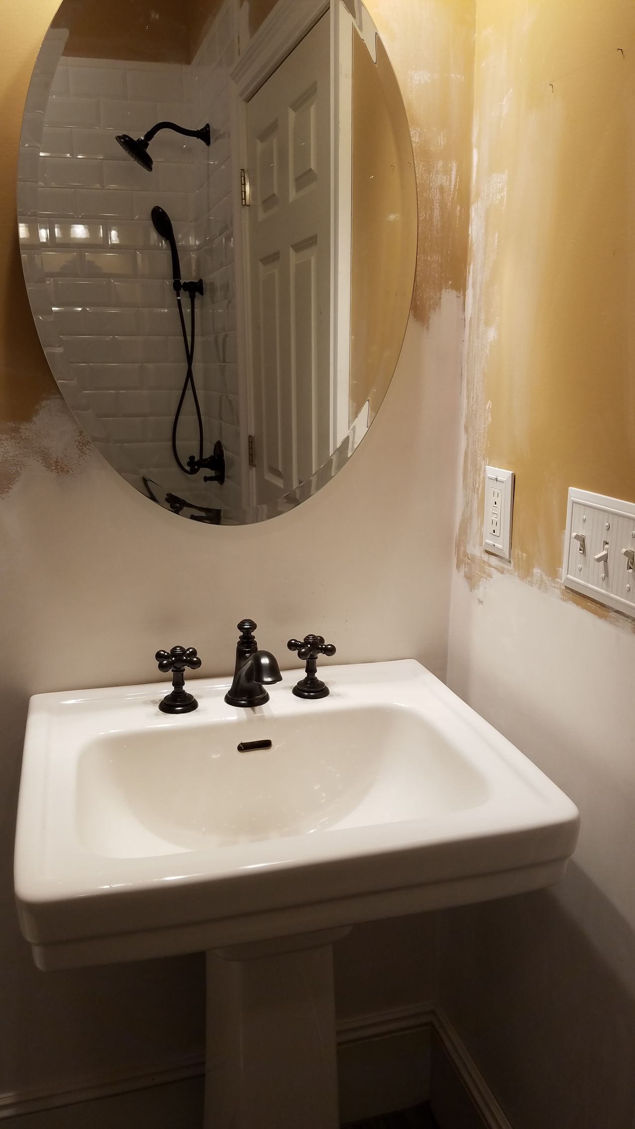 Small bathroom vanity with white sink, round mirror, and beige walls.