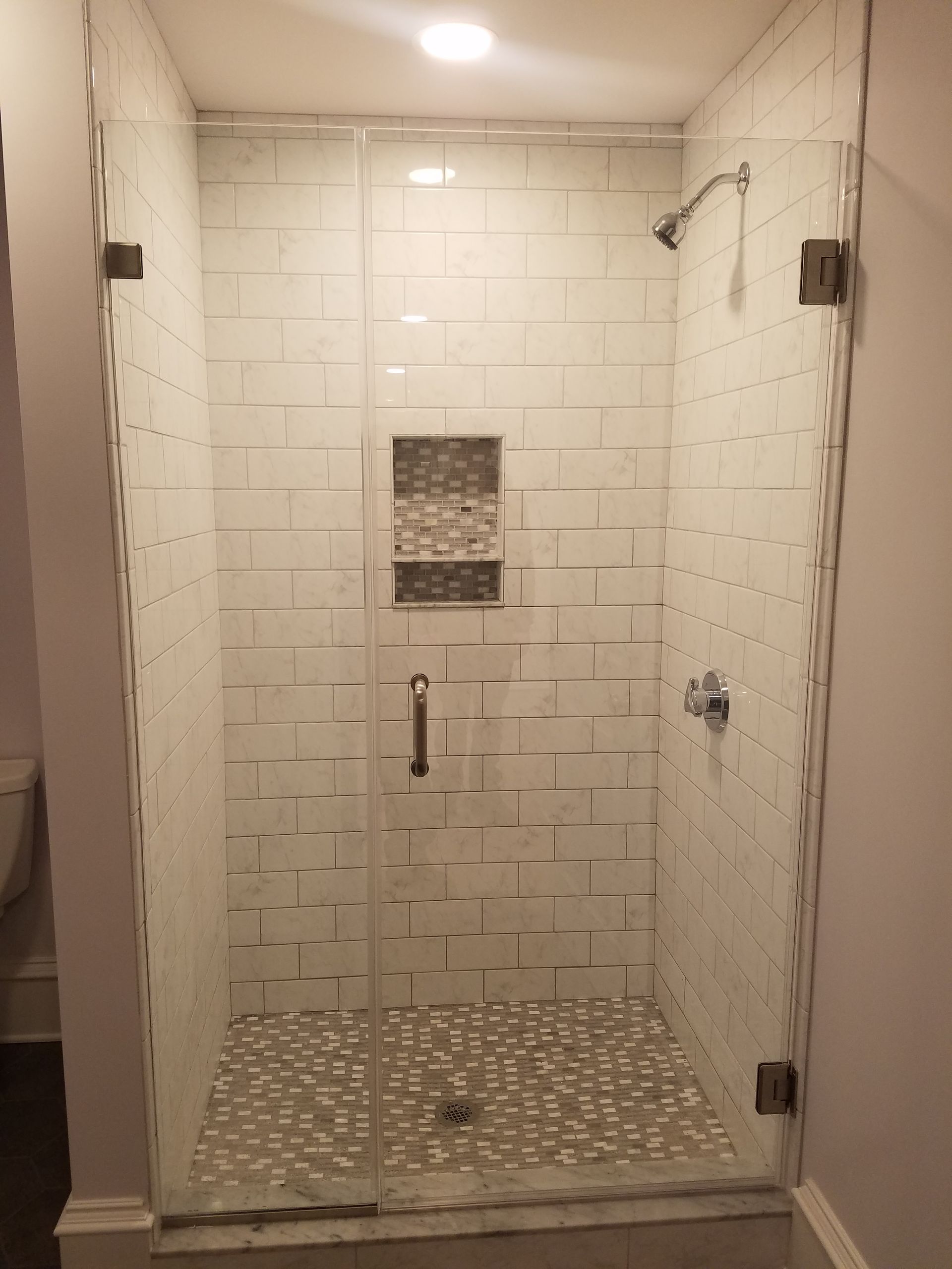 Tiled walk-in shower with pebble floor, built-in niche, and glassless entry.