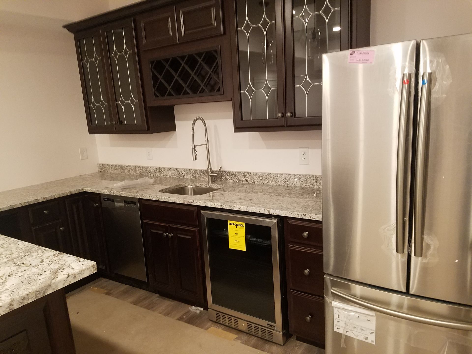 Modern kitchen with dark wood cabinets, granite counters, and stainless steel appliances.