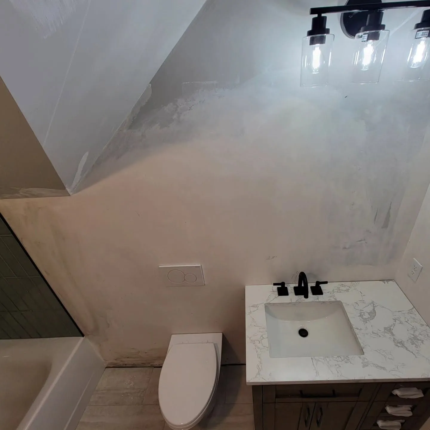 Bathroom with toilet, sink, and tub partially obscured by steam or fog
