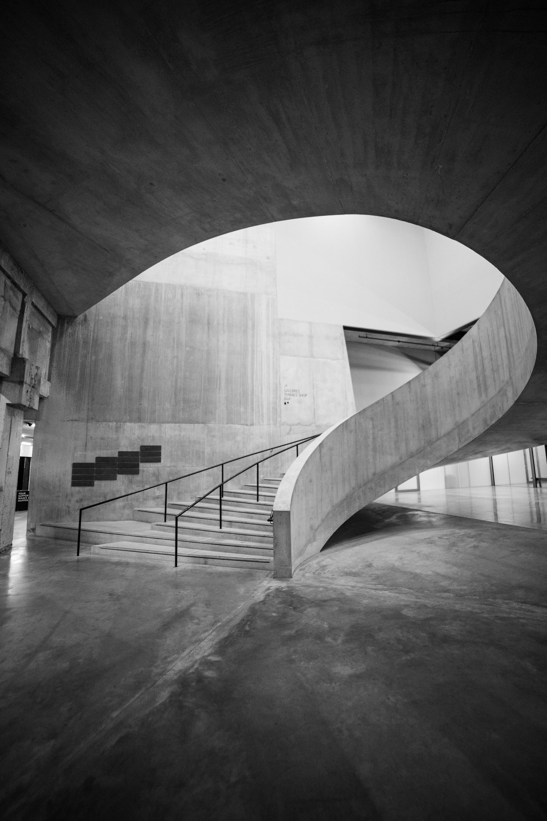 A black and white photo of a spiral staircase in a building.