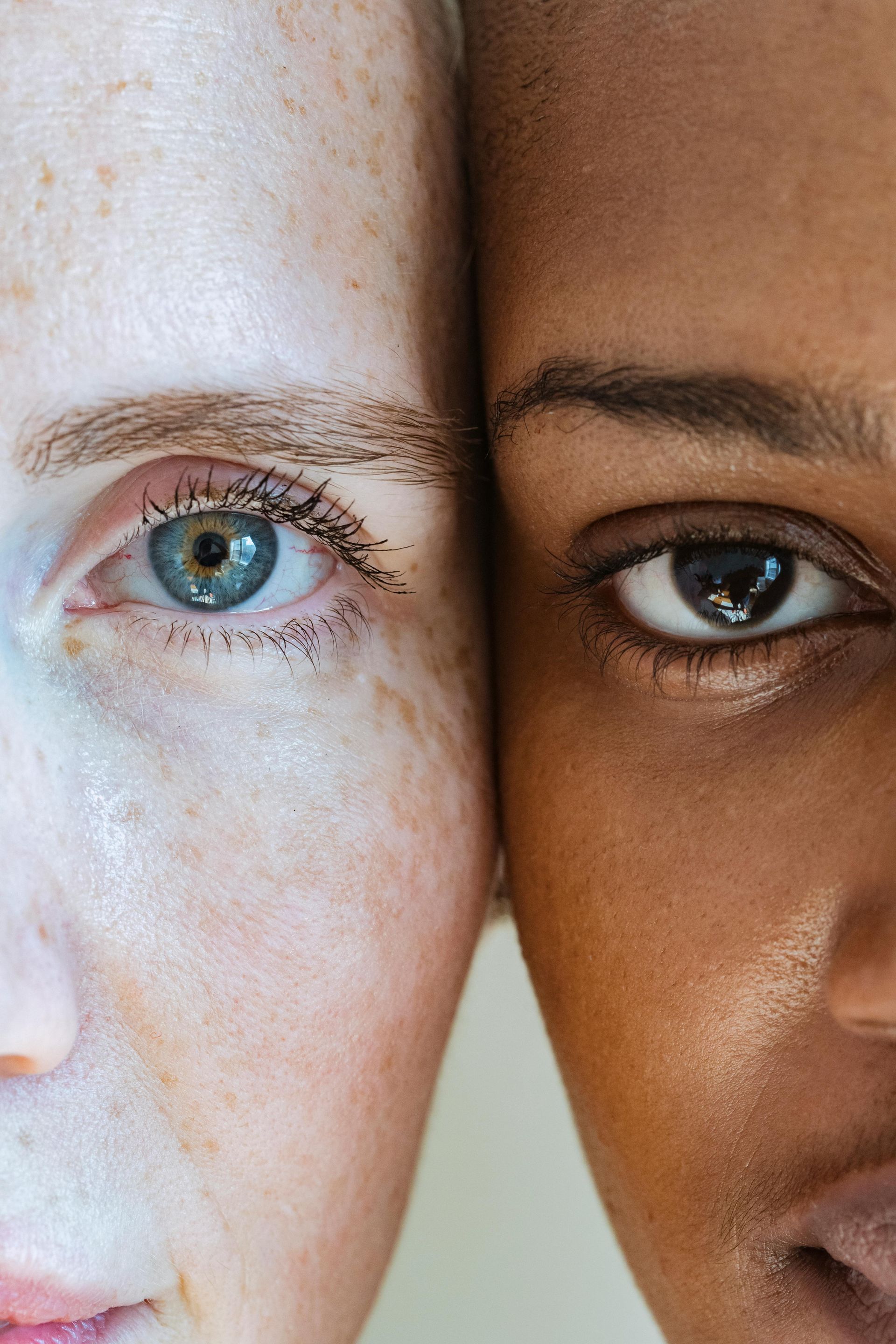 A close up of two women 's faces with different skin tones.