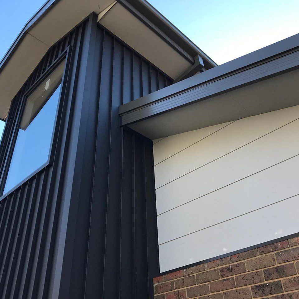 Dark gray vertical siding and white horizontal siding on a modern home exterior with a brick base.