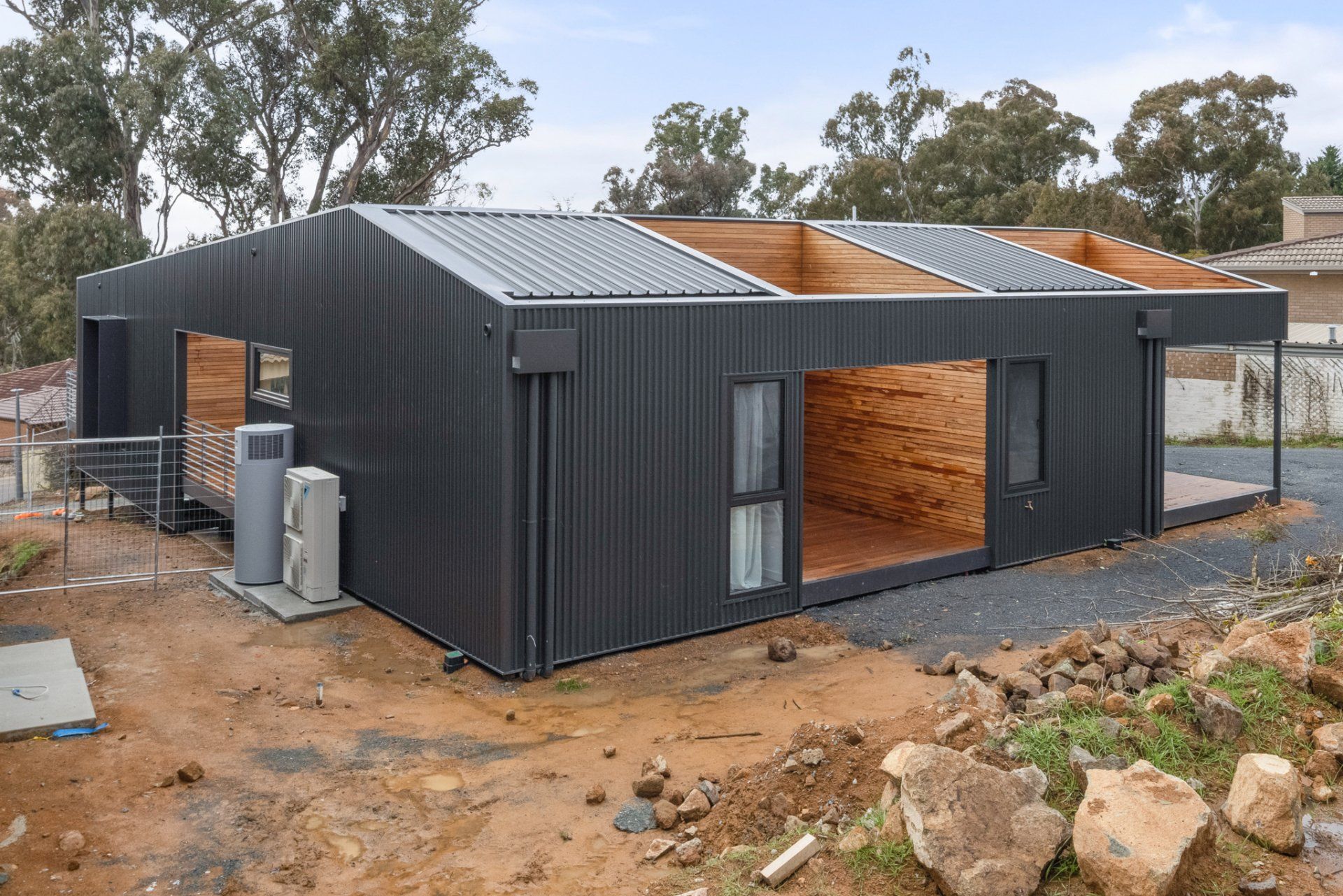 Black corrugated metal home under construction with exposed wood framing.