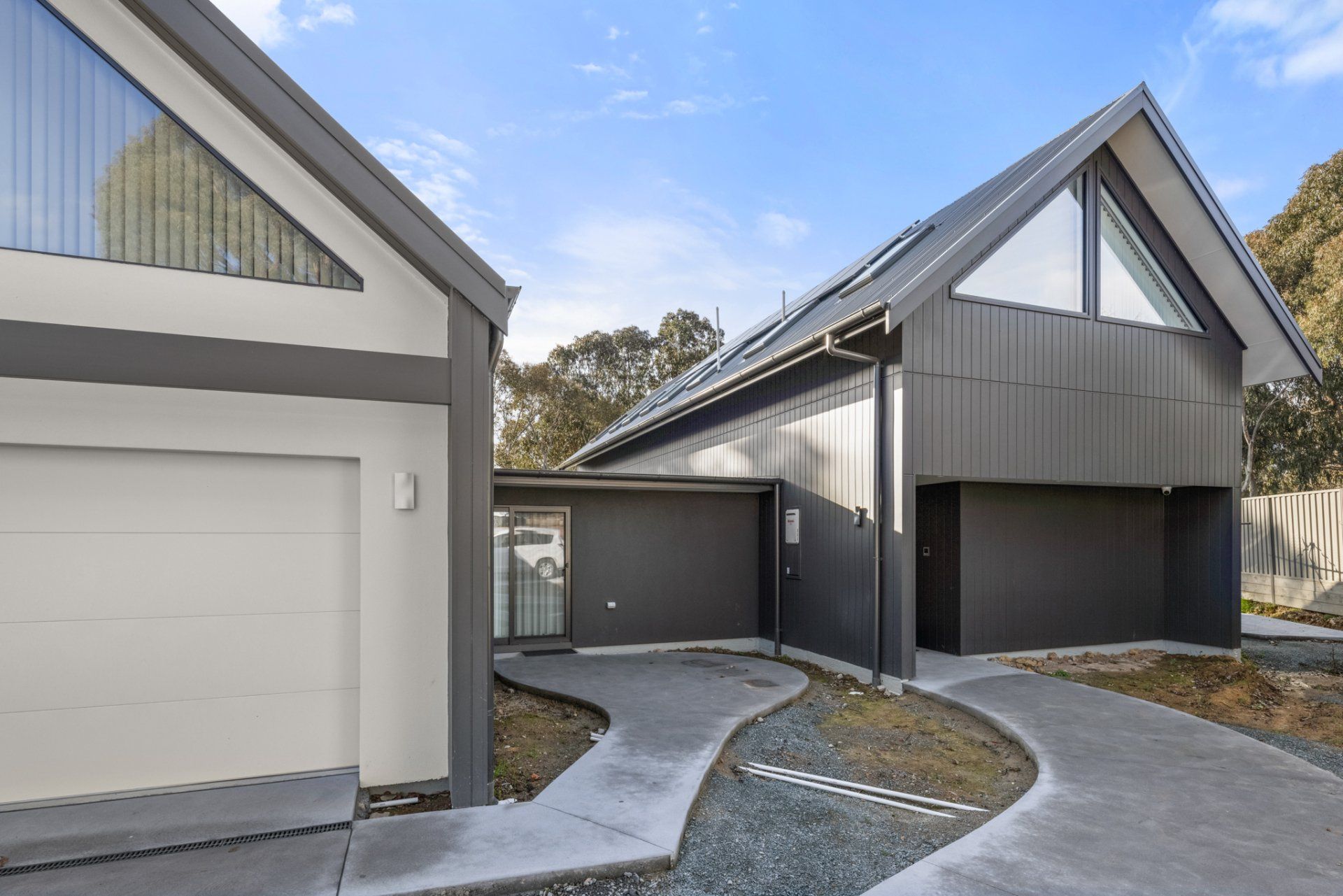 Modern gray house with angled roof and attached garage; concrete driveway.